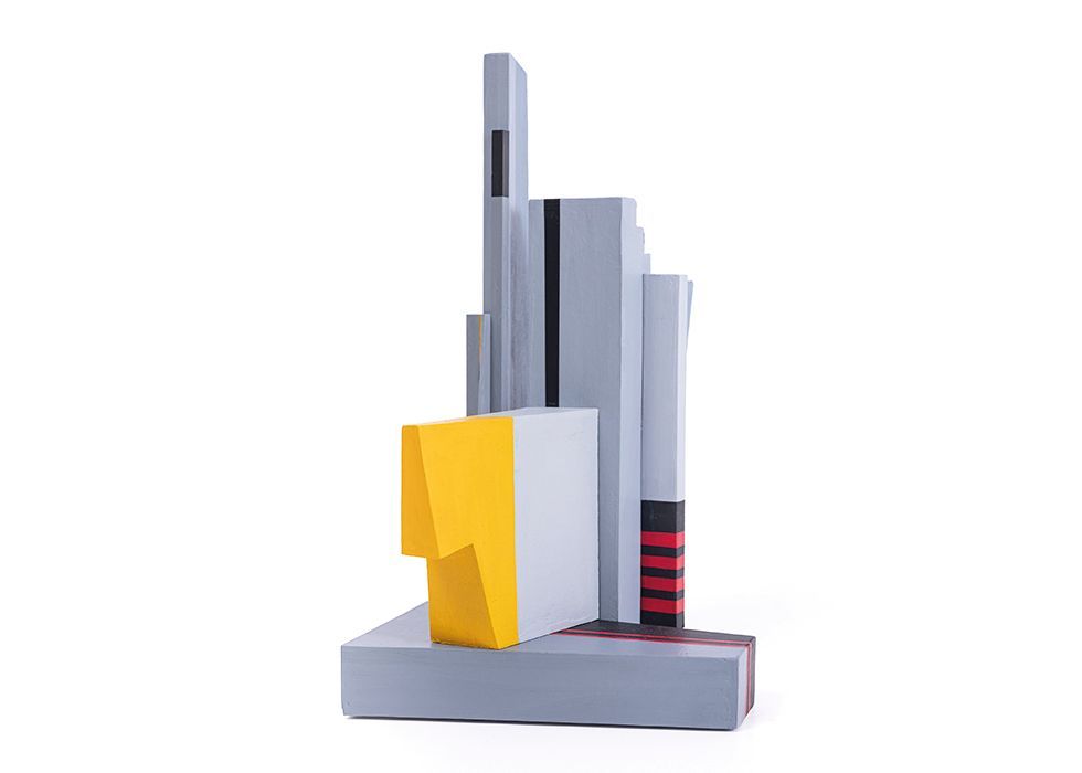 Abstracte sculptuur met grijze blokken, een gele vorm en rode accenten.