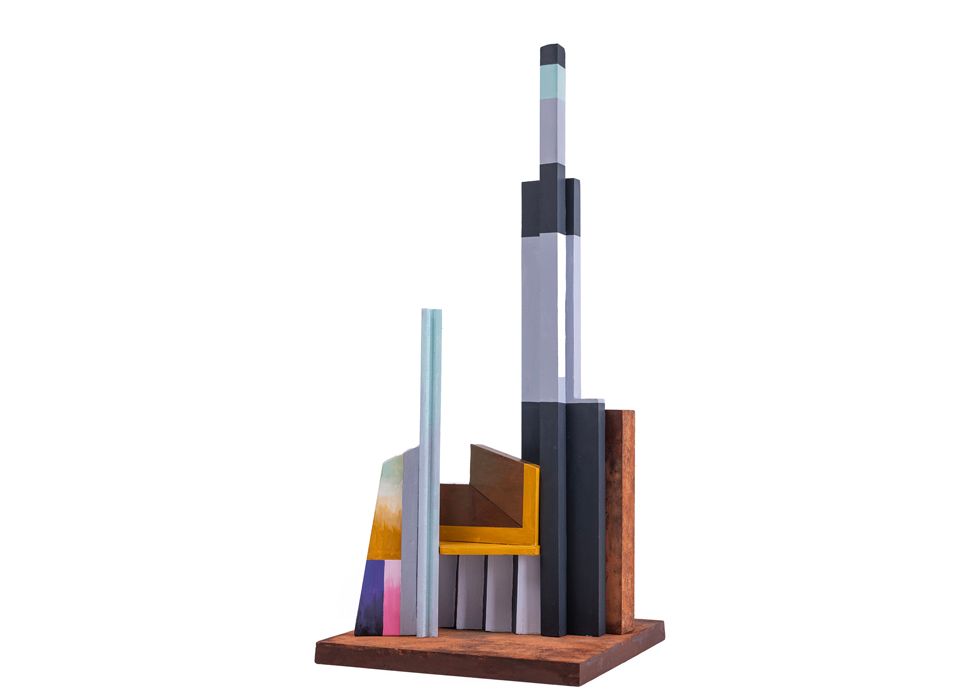 Abstracte sculptuur met verticale elementen van hout en metaal op een bruine sokkel.