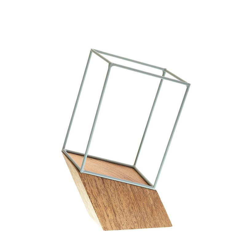 Hoekig metalen kubusframe op een houten blok met zichtbare houtnerf, tegen een witte achtergrond.
