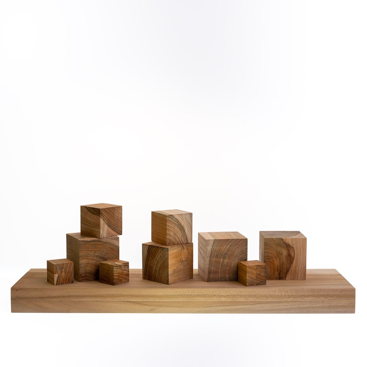 Houten blokken van verschillende afmetingen op een houten plank tegen een witte achtergrond.