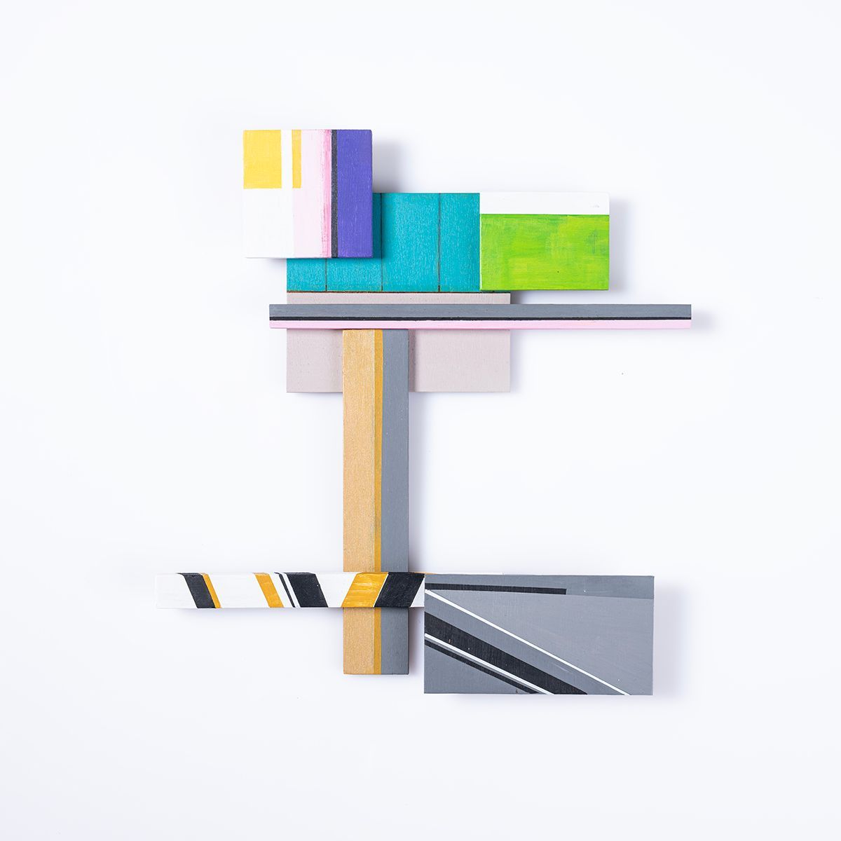 Geometrisch abstract kunstwerk met kleurrijk beschilderde houten blokken op een witte achtergrond.