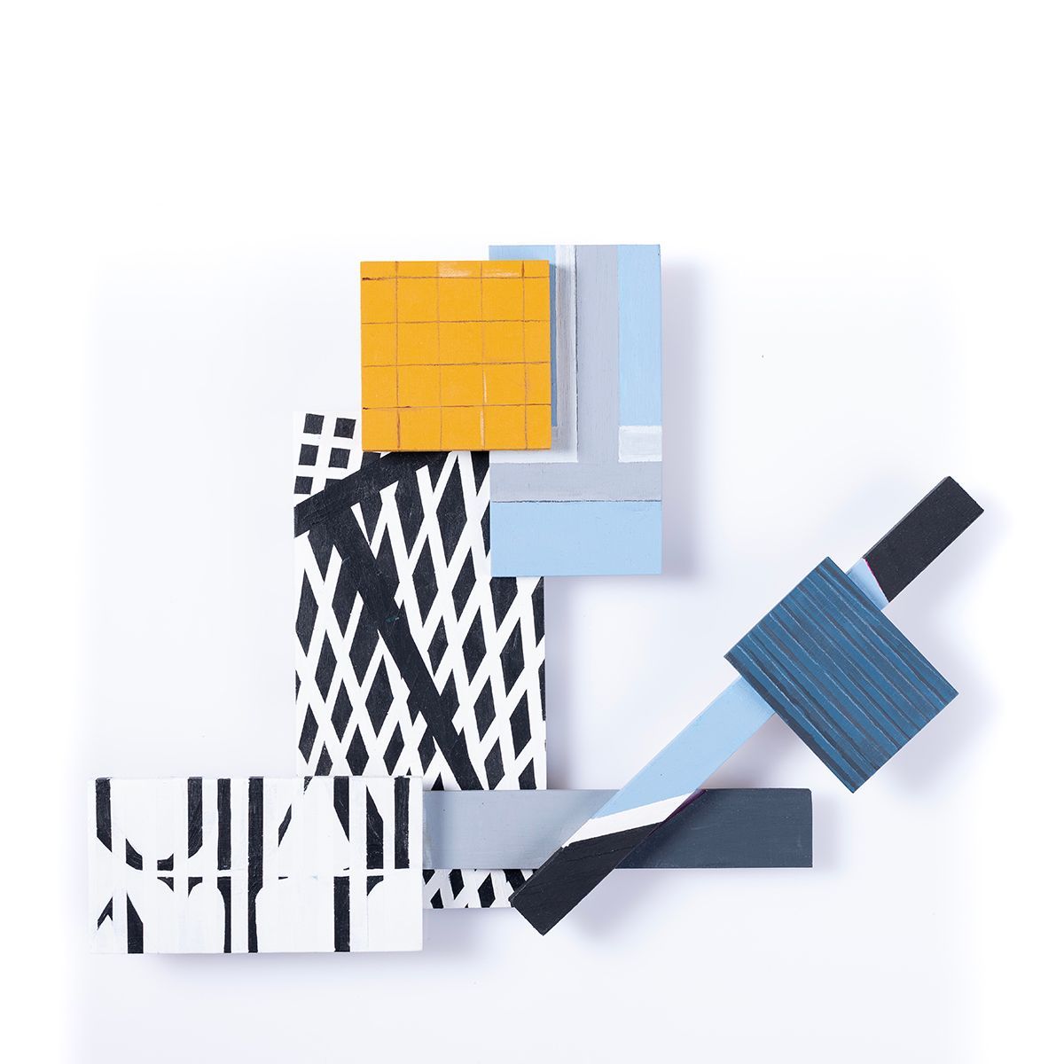 Abstracte muurkunst met geometrische vormen in geel, blauw, zwart, wit en grijs, die over elkaar heen zijn geplaatst.
