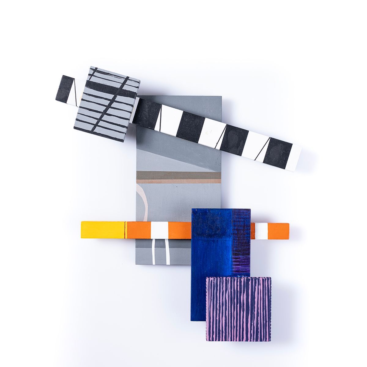 Abstracte houten sculptuur met geometrische vormen in diverse kleuren tegen een witte achtergrond.