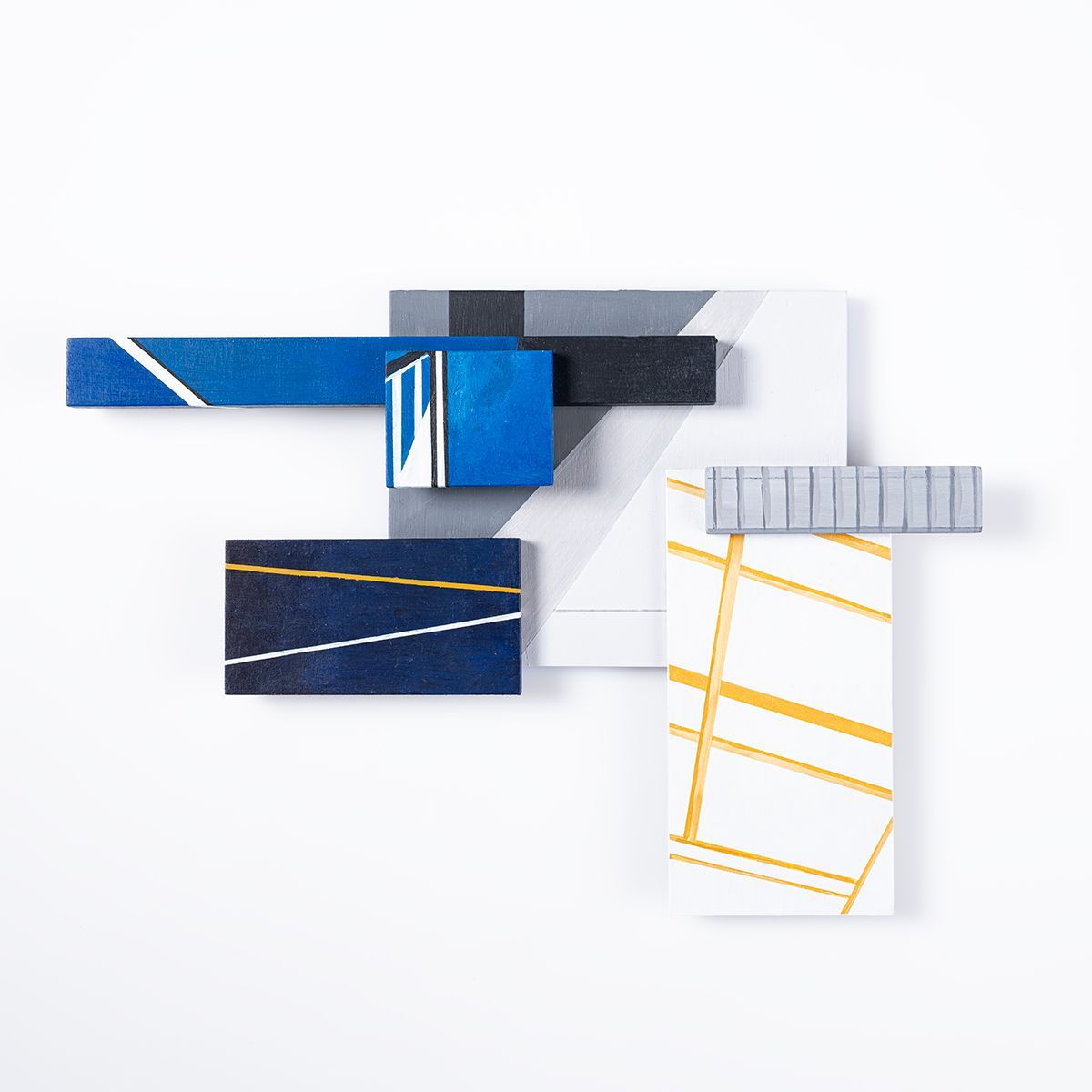 Abstracte geometrische wanddecoratie met blauwe, witte, grijze en gouden blokken.