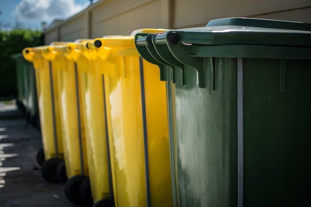 A Row of Yellow and Green Trash Cans Are Lined Up in a Parking Lot — Bin in a Bath in Saint Albans Park, VIC
