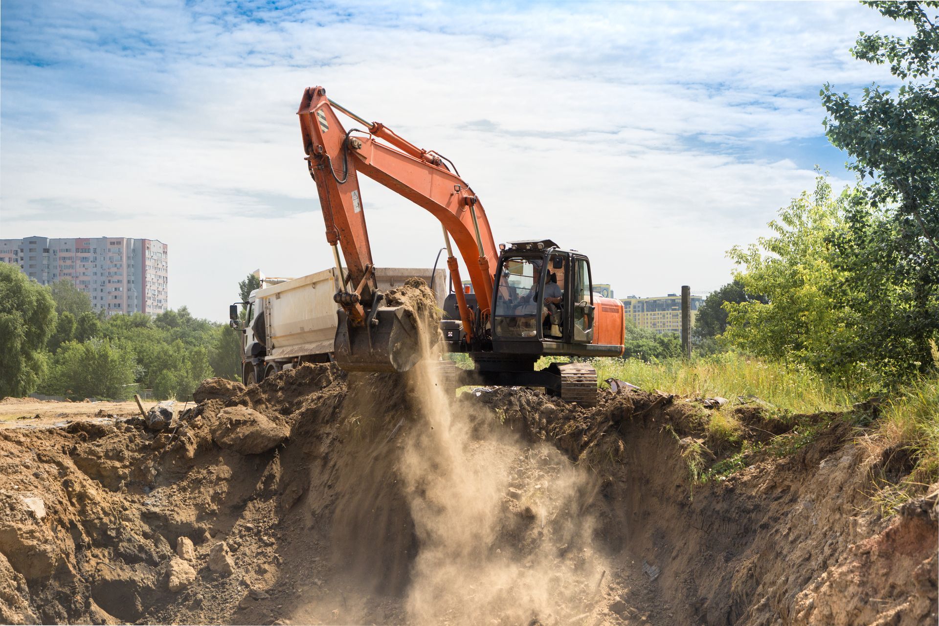 Orange excavator loading dirt into a dump truck at a construction site. Orange excavator loading dirt into a dump truck at a construction site.