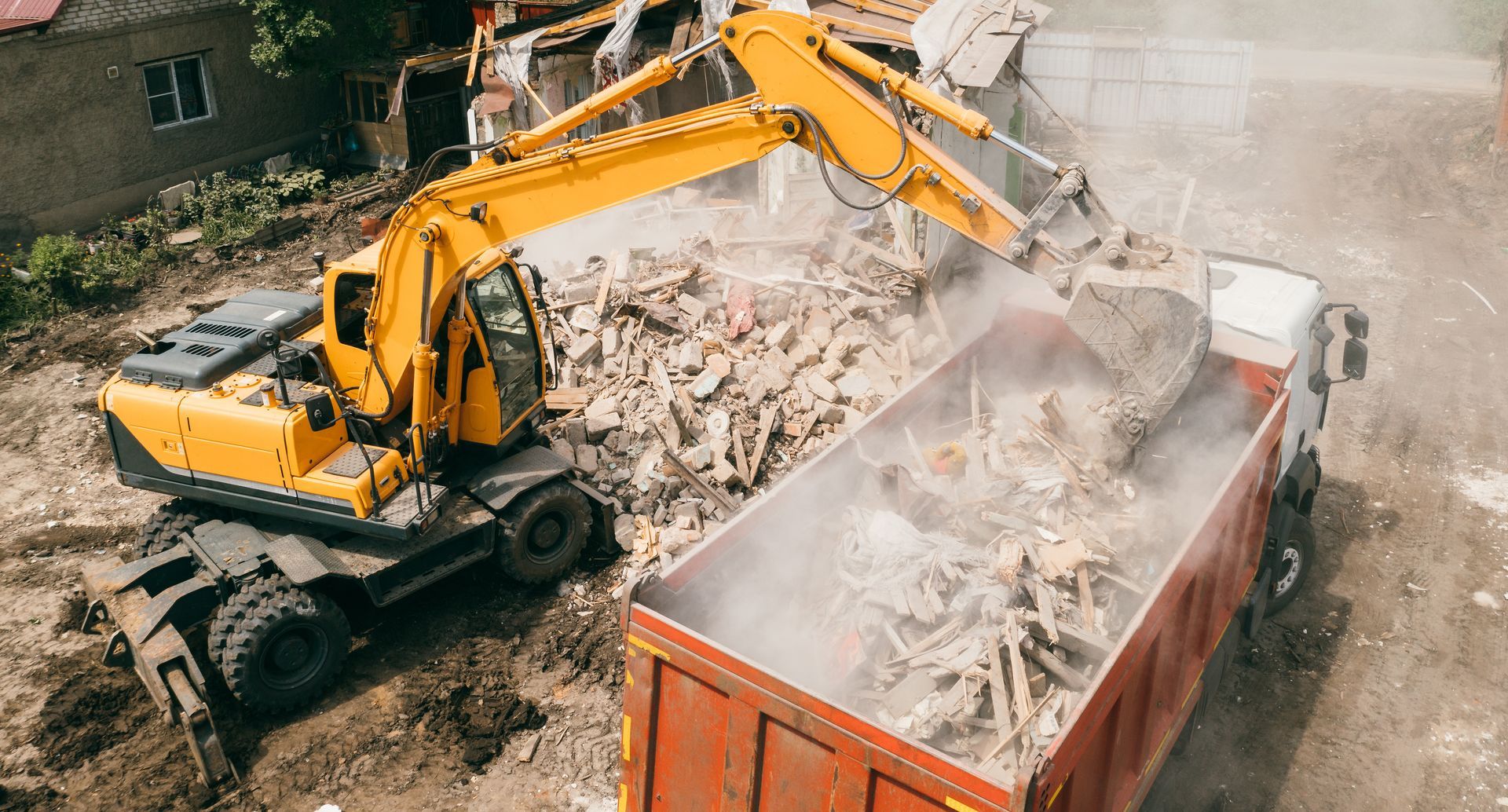 Yellow excavator loading debris into a red dump truck at a construction site. Yellow excavator loading debris into a red dump truck at a construction site.