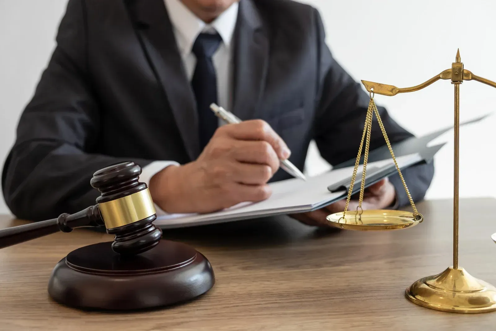 A judge is sitting at a table with a gavel and scales of justice.