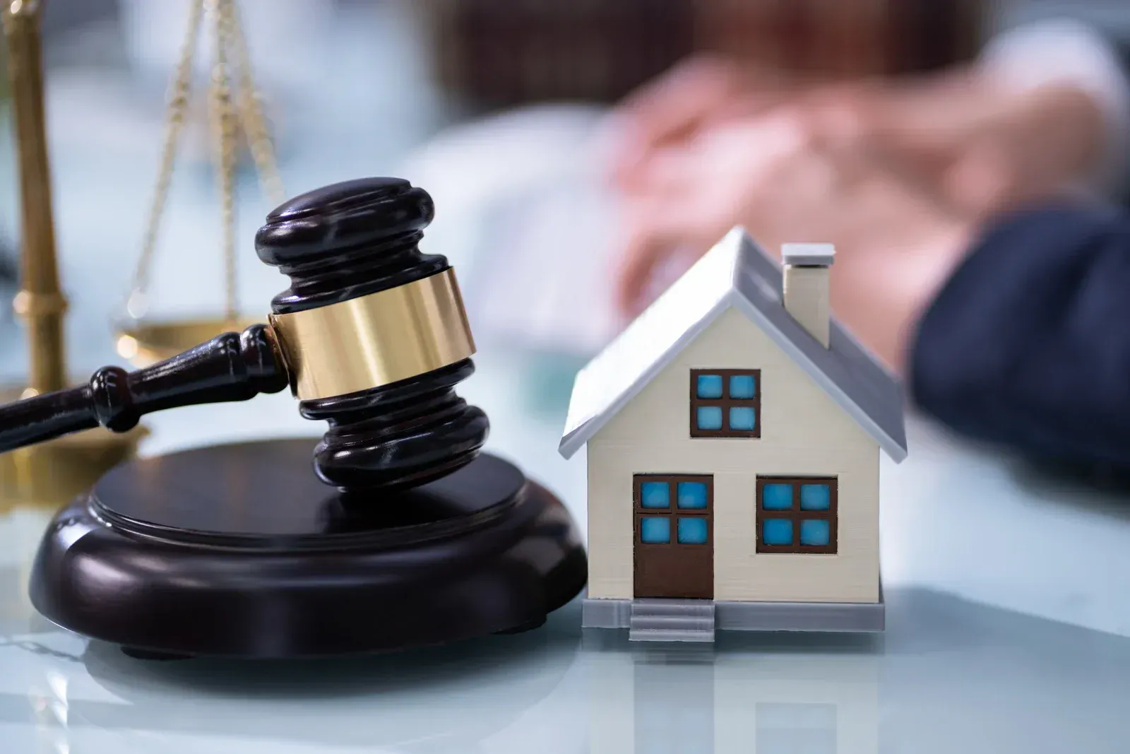 A small model house is sitting next to a judge 's gavel on a table.