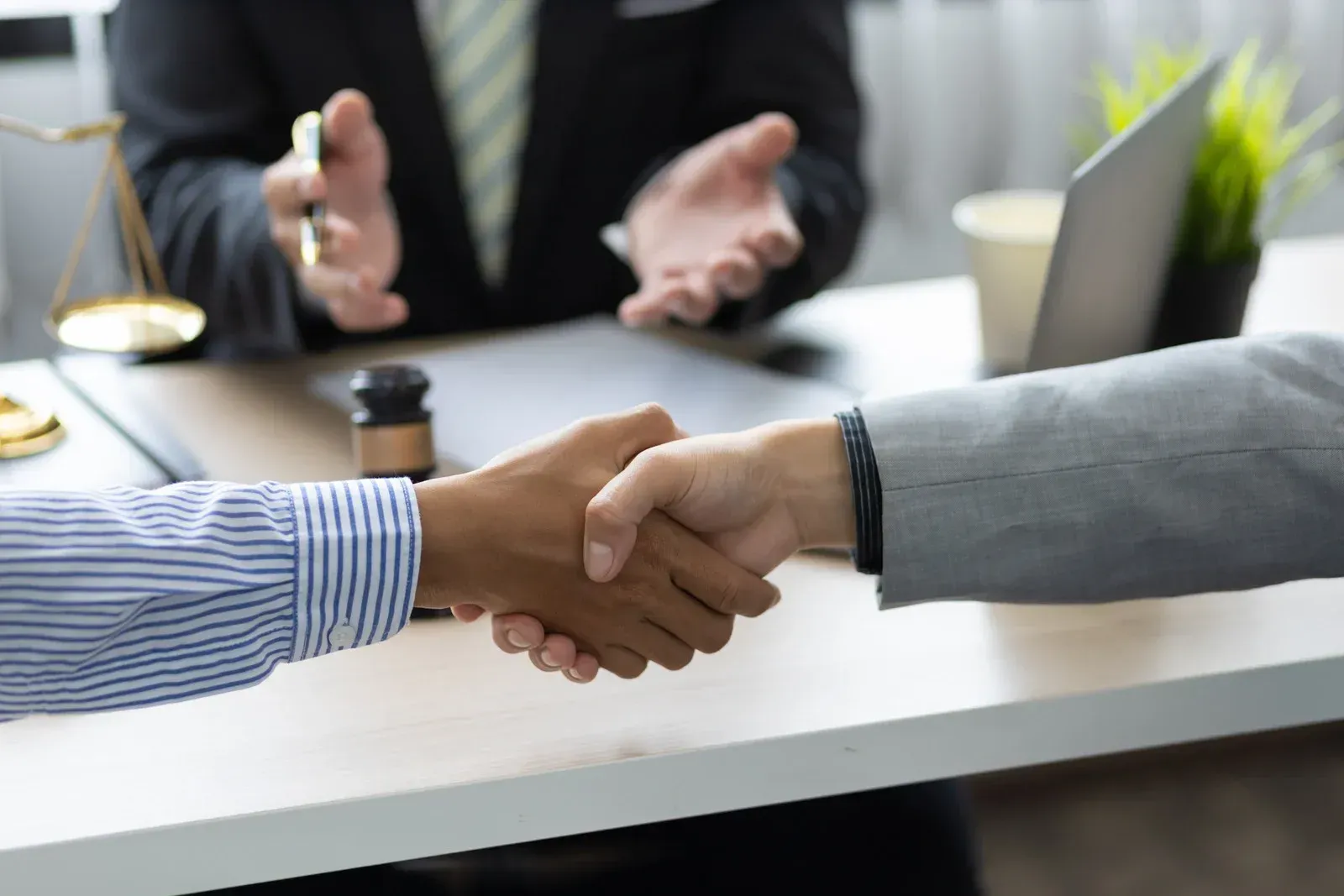 A man and a woman are shaking hands in front of a lawyer.