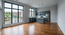 Two cleaners in green overalls and yellow gloves wiping a table and mopping a living room floor