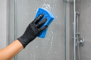 Person in yellow gloves cleaning a mirror with soapy foam