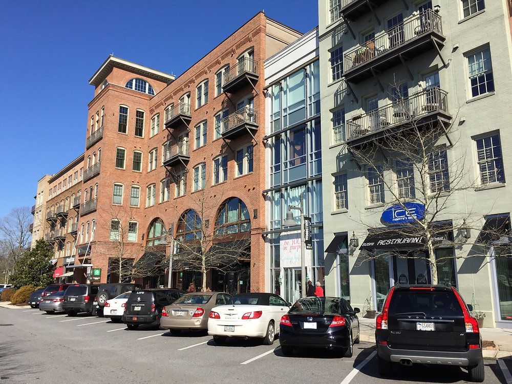 Urban street with parked cars and brick apartment buildings in daylight