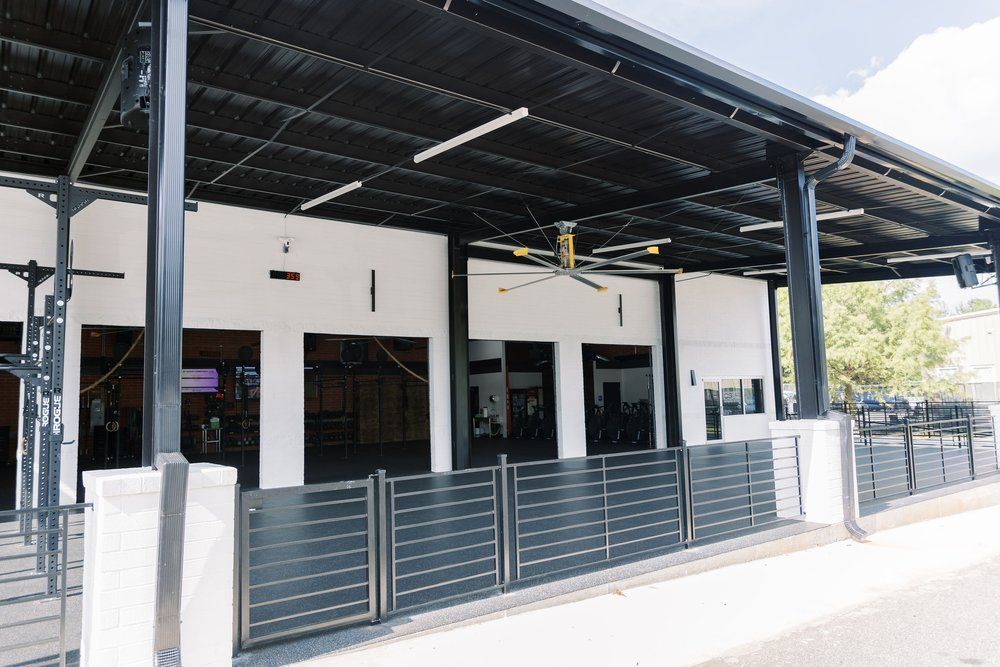 Modern building exterior with black roof, white walls, and gray metal fence in bright daylight