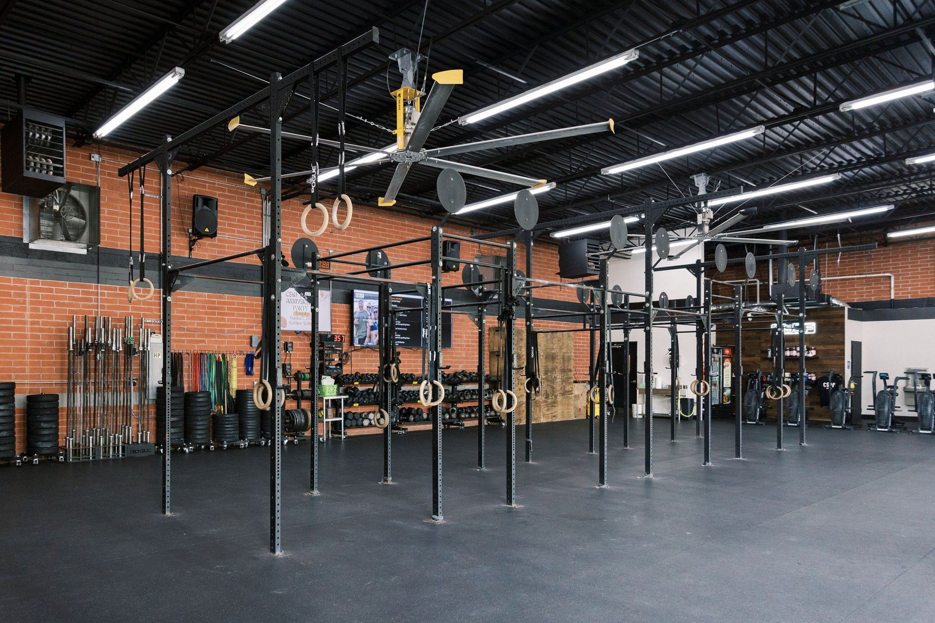 Empty gym interior with pull-up rigs, hanging rings, and exposed brick walls
