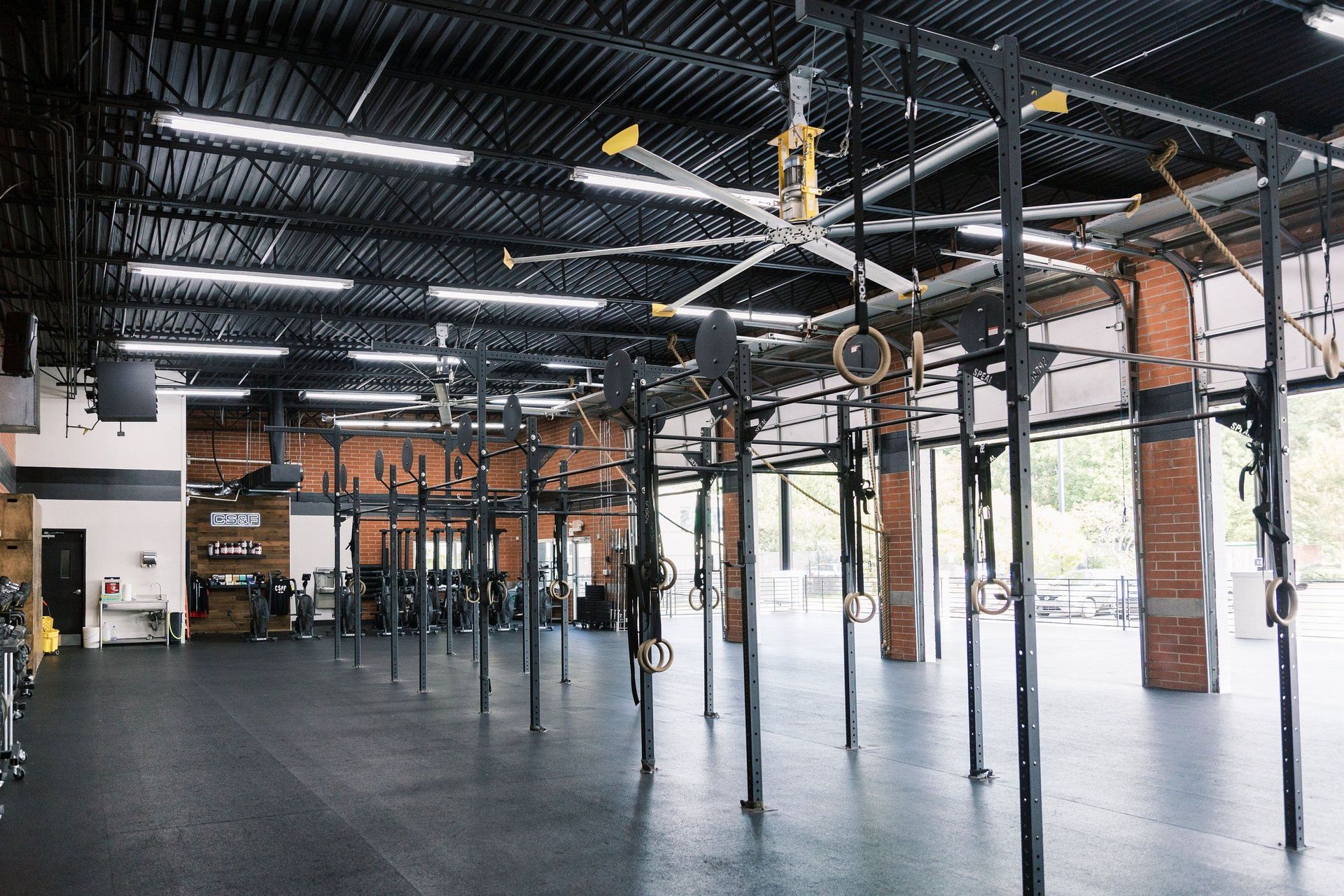 Spacious industrial gym with hanging rings, metal beams, and a polished concrete floor