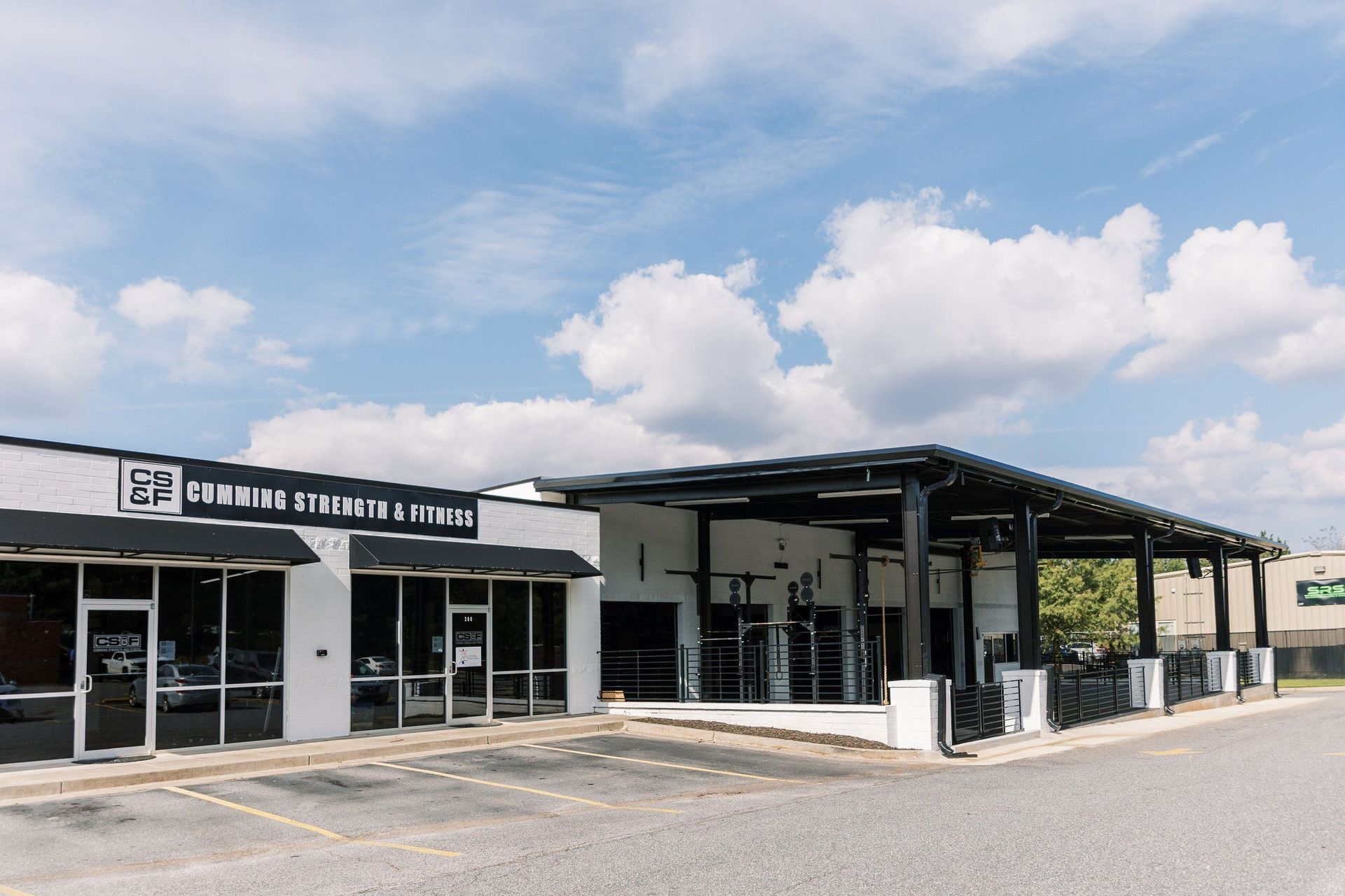 Modern roadside storefront with black awning and outdoor seating under a partly cloudy sky
