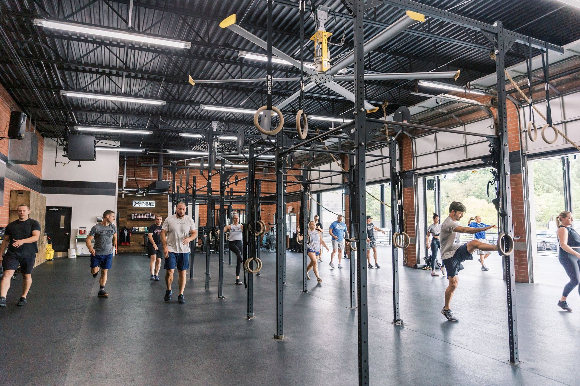 People exercising in a bright gym with pull-up rigs and large windows