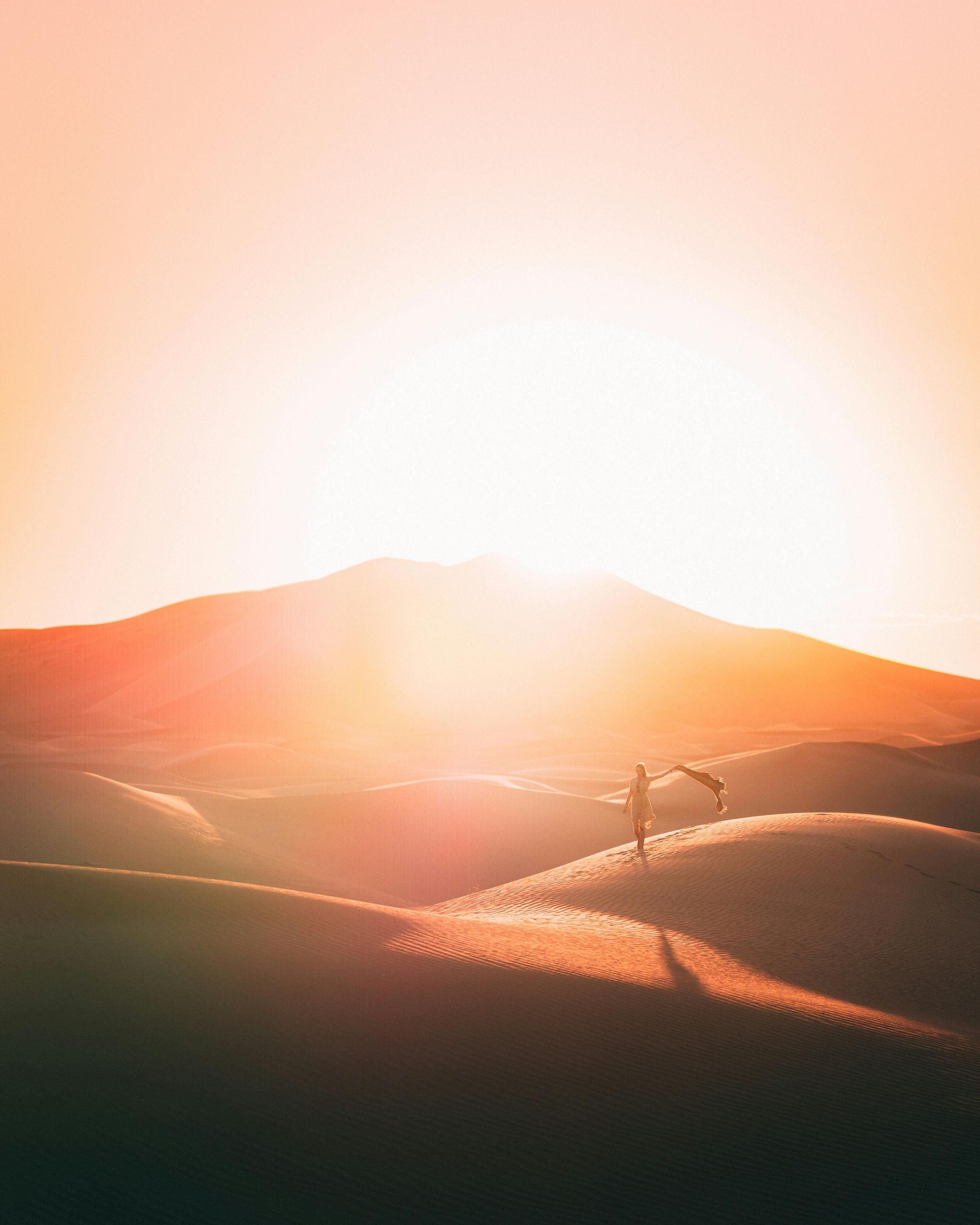 A blazing sun shining down from above a mountain on a desert scene 