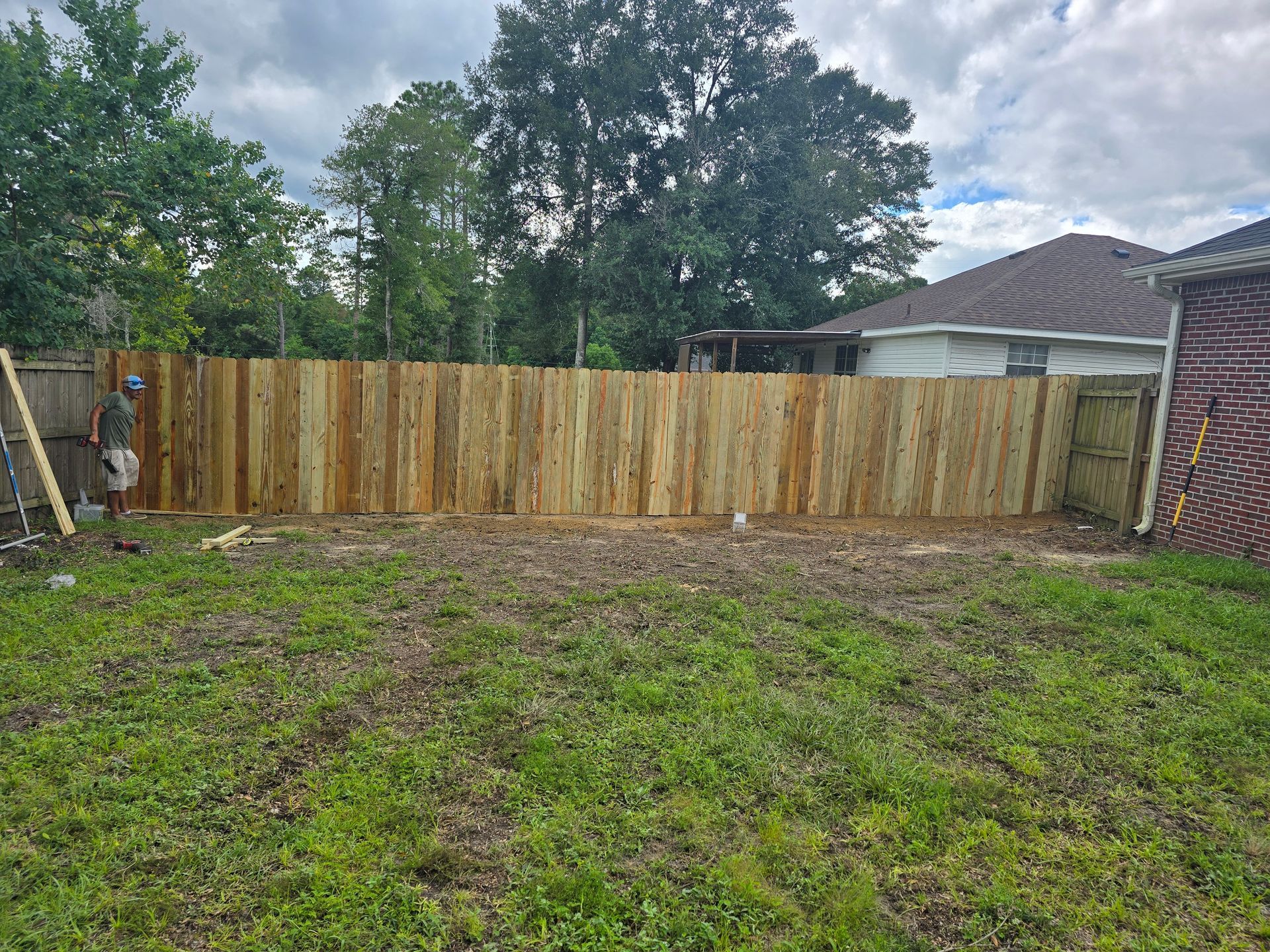 Lush green backyard with white picket fence, open gate, and blue sky with wispy clouds. Lush green backyard with white picket fence, open gate, and blue sky with wispy clouds.