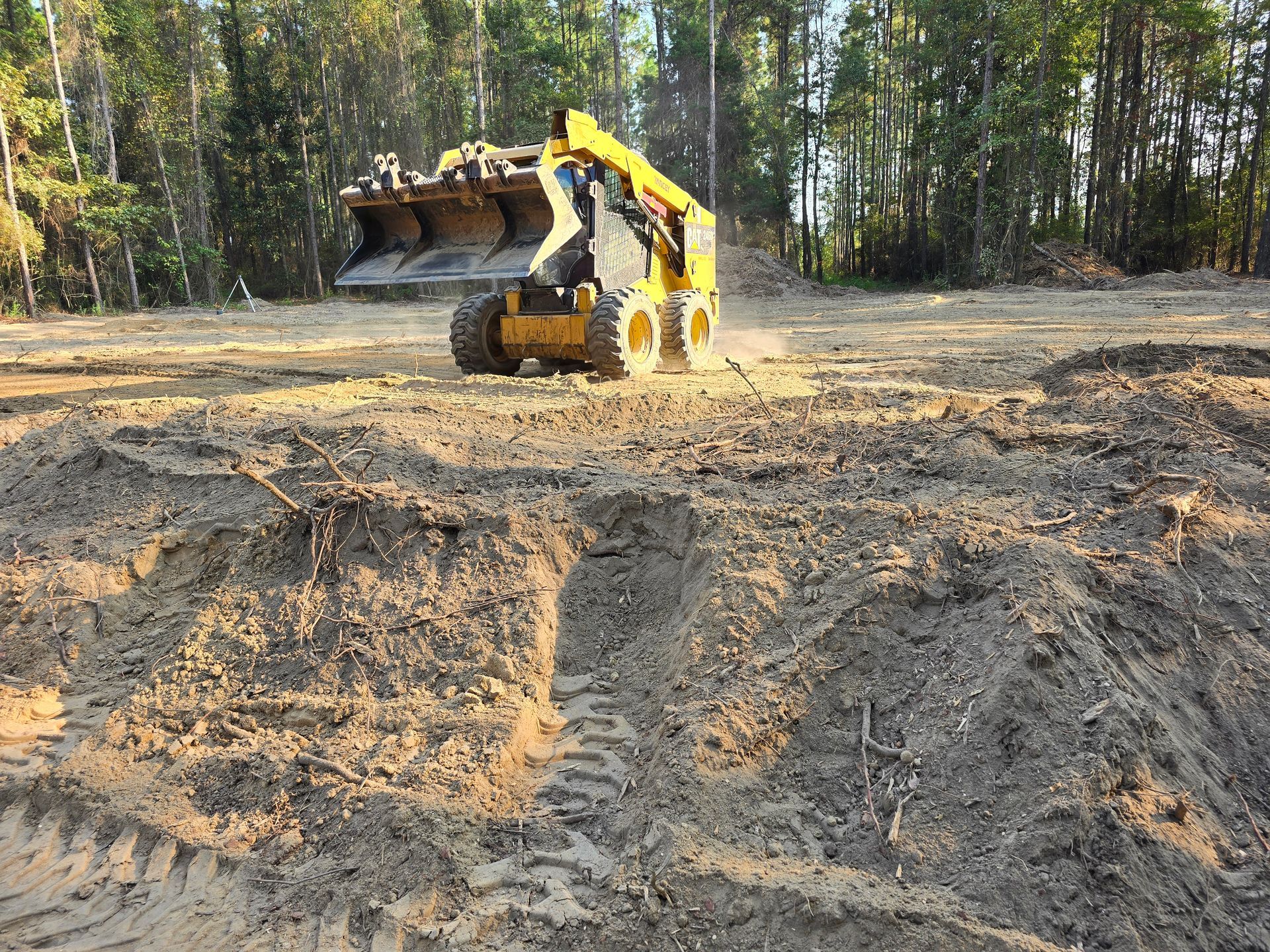 Yellow excavator on tracks; construction site with dirt pile and trees in background. Yellow excavator on tracks; construction site with dirt pile and trees in background.