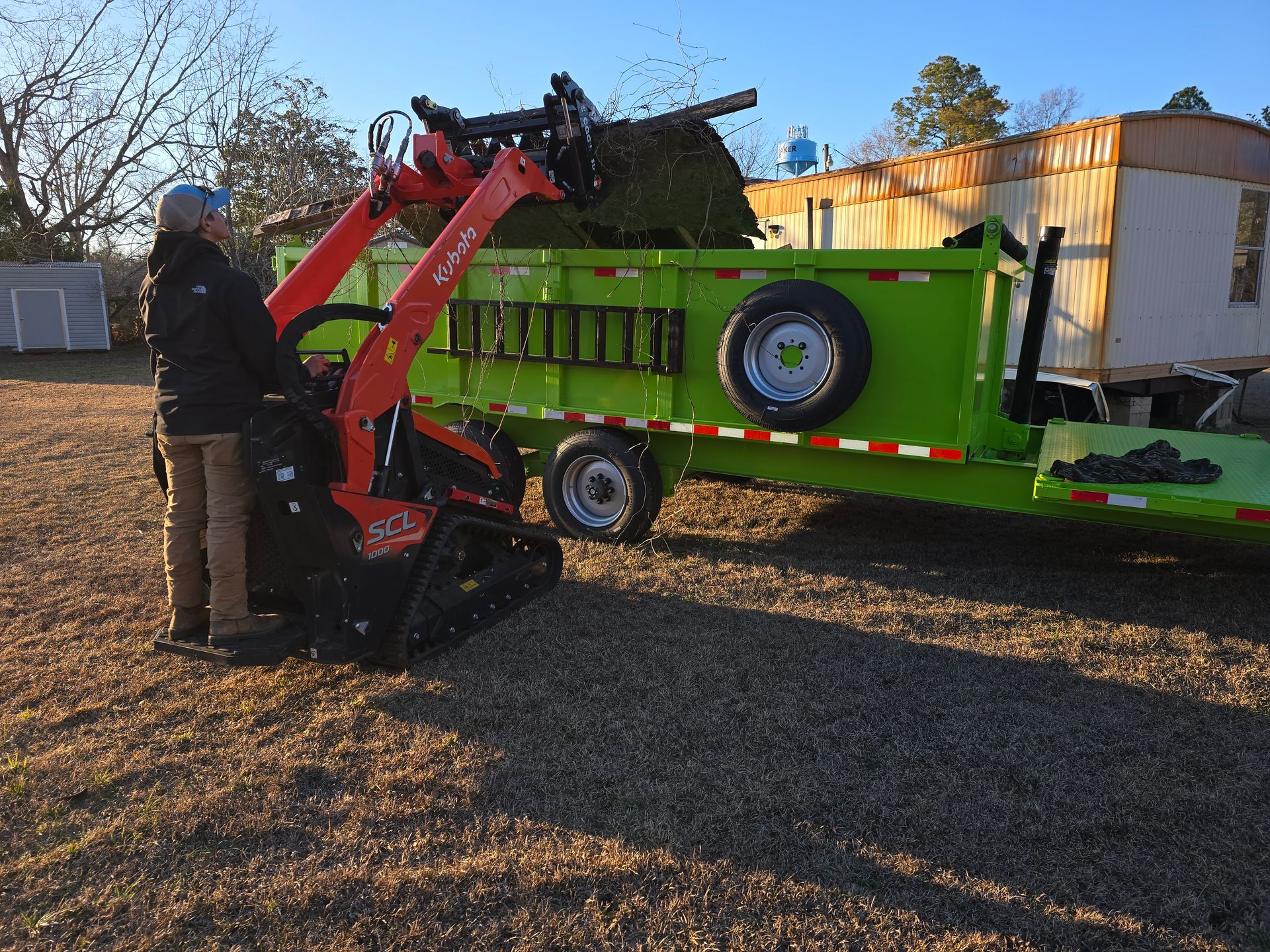 Excavator demolishing a structure, debris pile. Dusty scene with trees and a vehicle in the background. Excavator demolishing a structure, debris pile. Dusty scene with trees and a vehicle in the background.