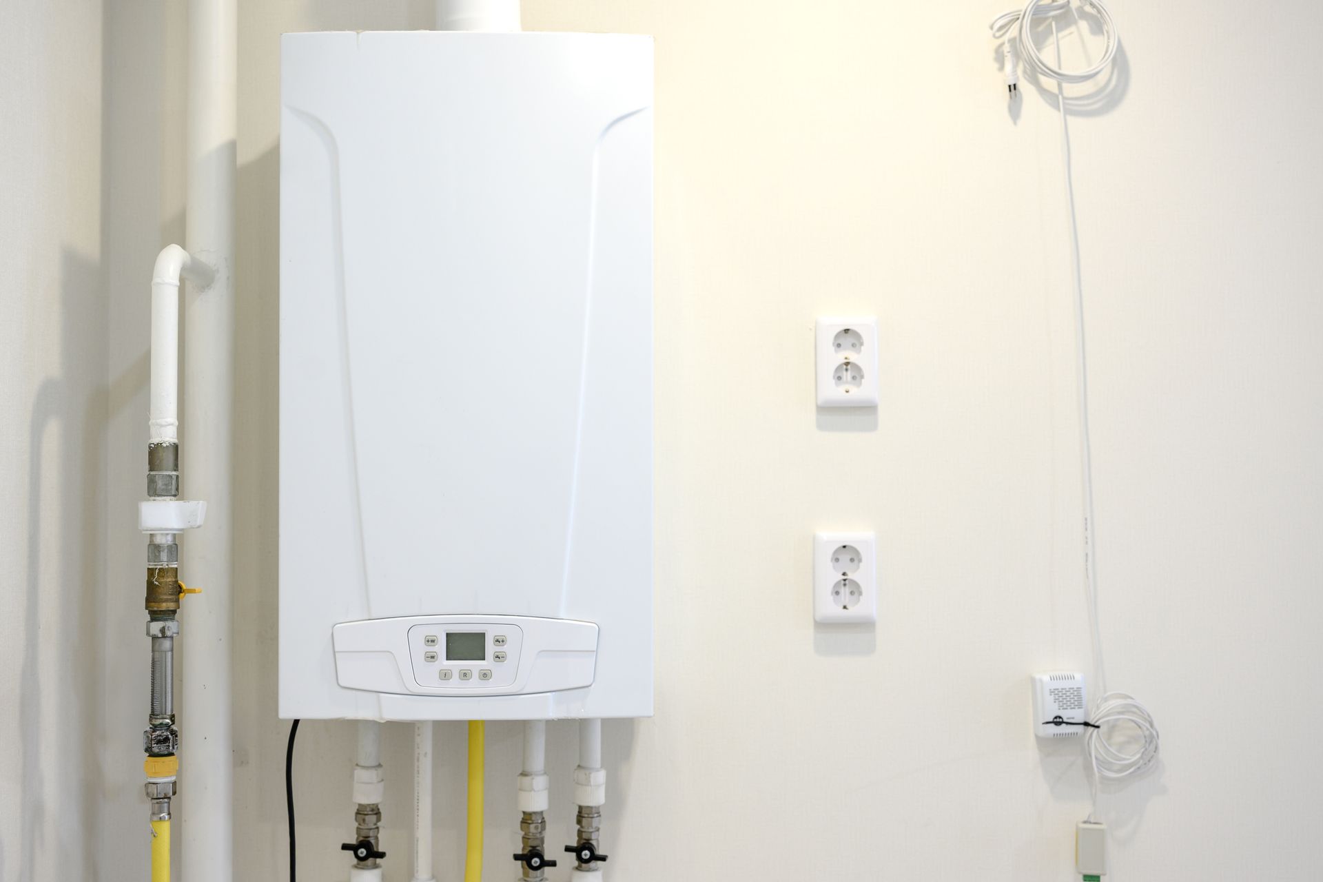 Wall-mounted gas boiler connected to plumbing lines, providing efficient home heating. Wall-mounted gas boiler connected to plumbing lines, providing efficient home heating.