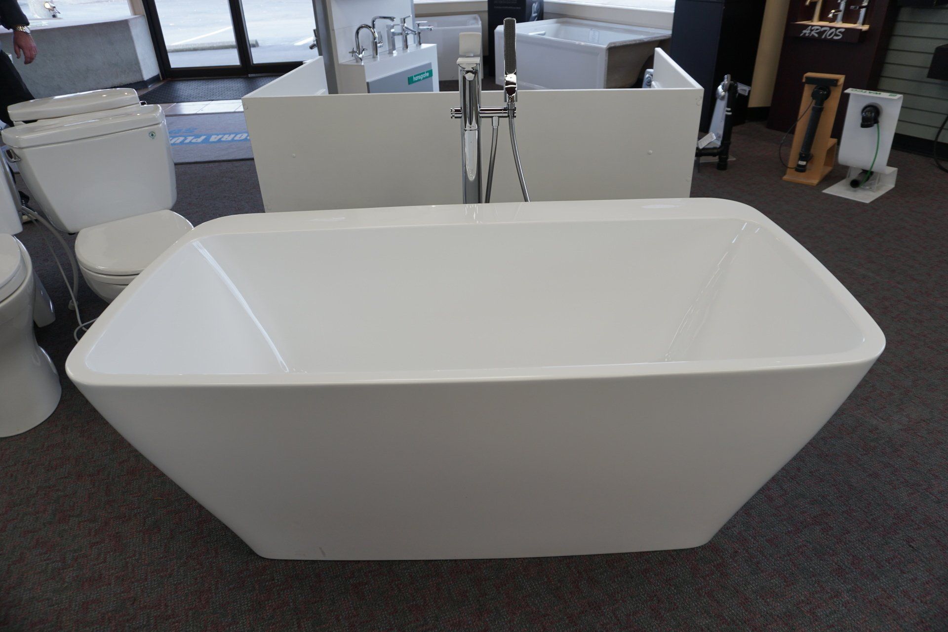 A white bathtub is sitting in a bathroom next to a toilet.