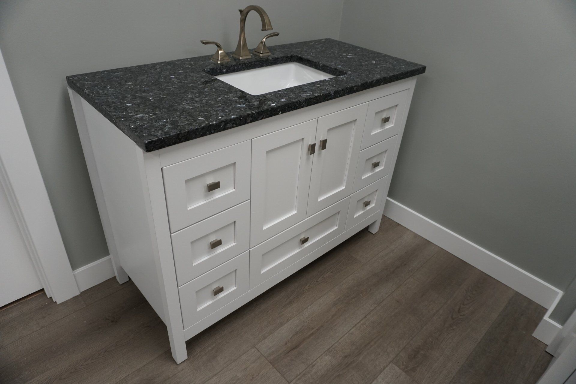 A bathroom vanity with a black counter top and a white sink.