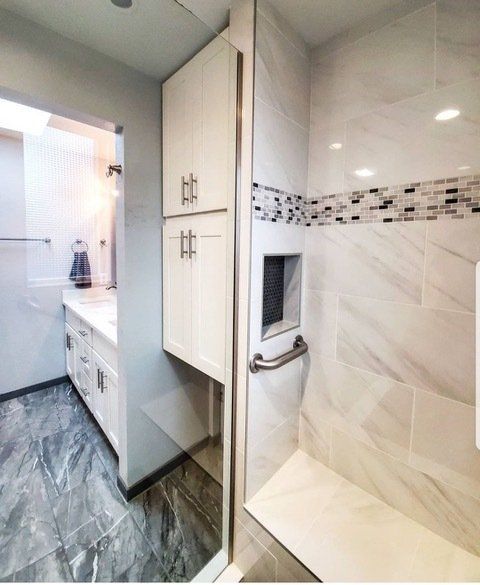 A bathroom with a walk in shower and a sink