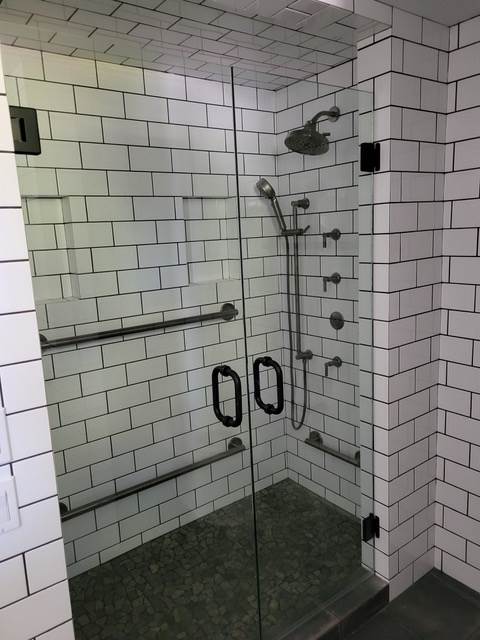 A bathroom with white bricks and a walk in shower with a glass door