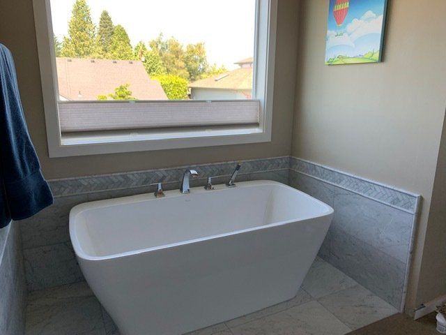 A white bathtub in a bathroom next to a window.