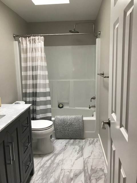 A bathroom with a toilet , sink , shower and bathtub.