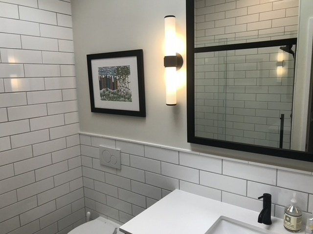 A bathroom with white tiles and a picture on the wall