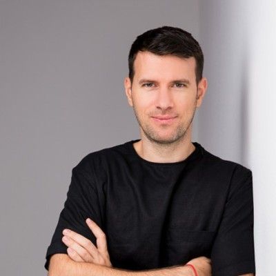 A man in a black shirt is leaning against a wall with his arms crossed.