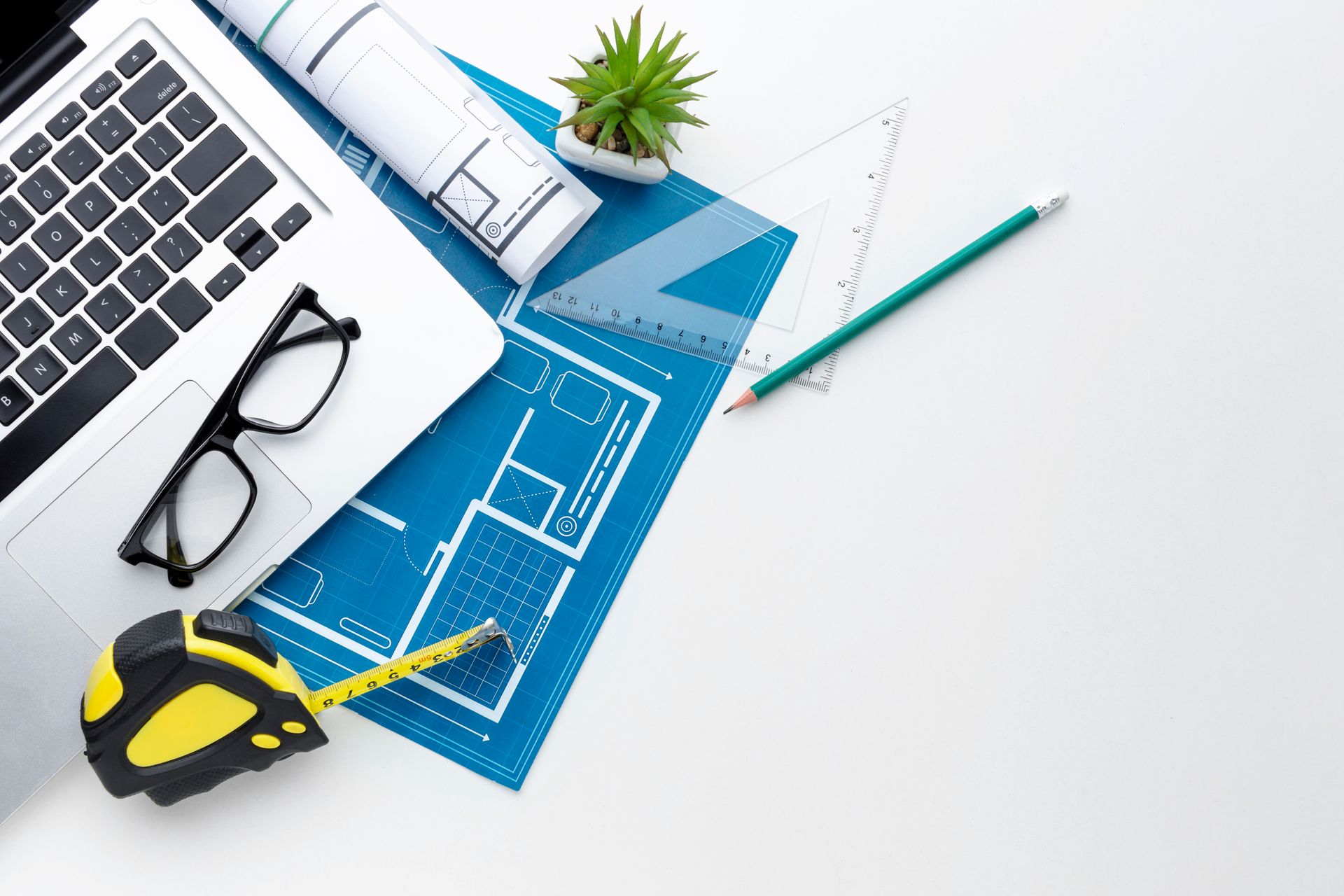 A laptop , glasses , a tape measure , a ruler , and a pencil are on a table.