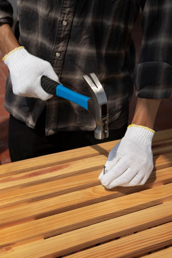 A man is using a hammer to hammer a nail into a piece of wood.