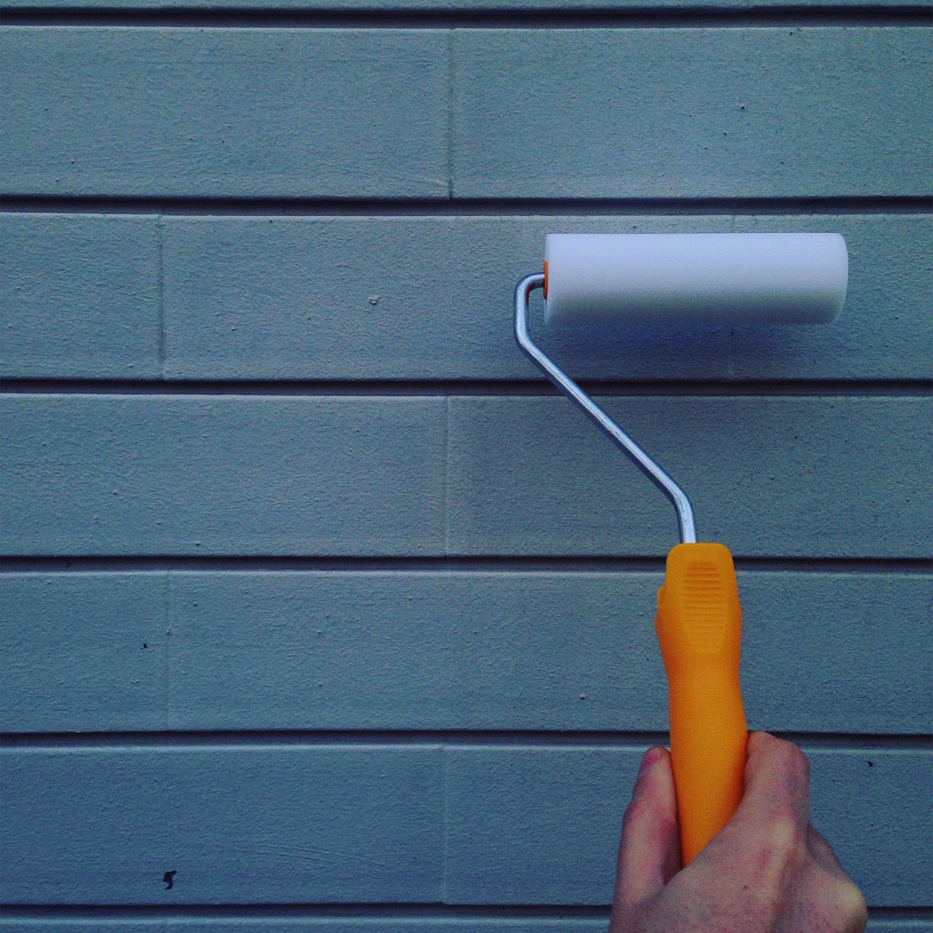 A person is painting a wall with a paint roller