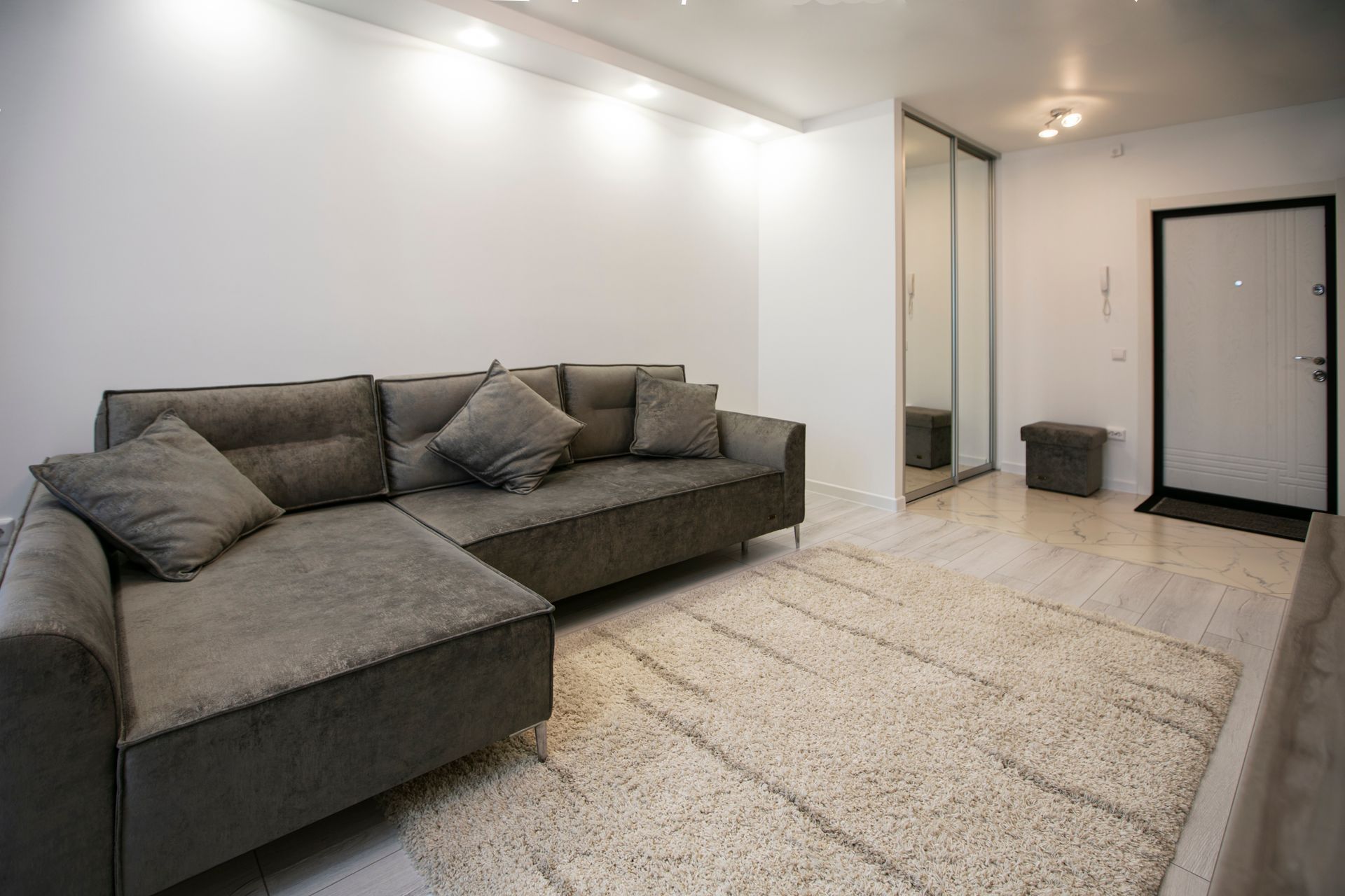 A living room with a couch , shelves , and stairs.