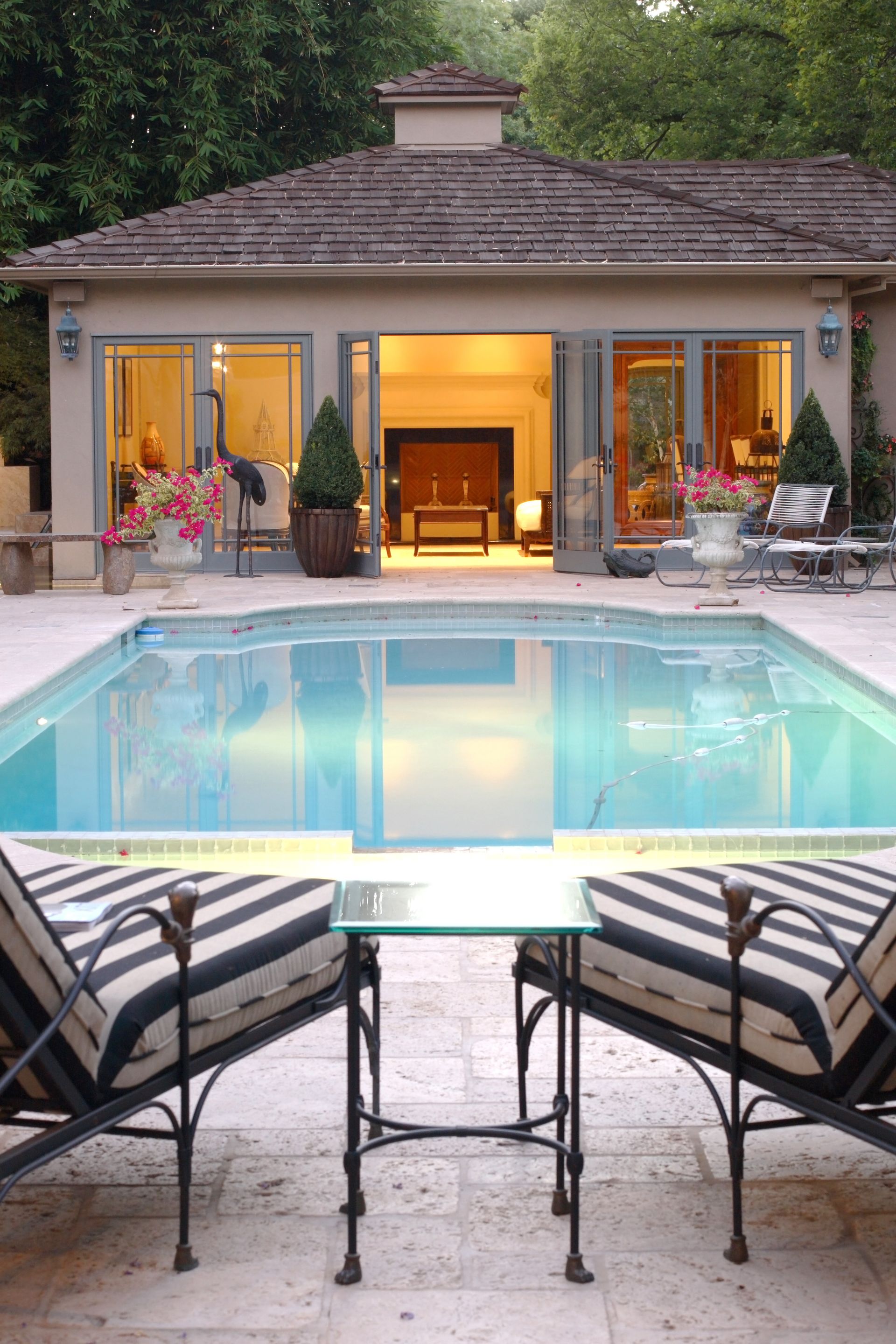 A man is sitting on a bench next to a swimming pool.