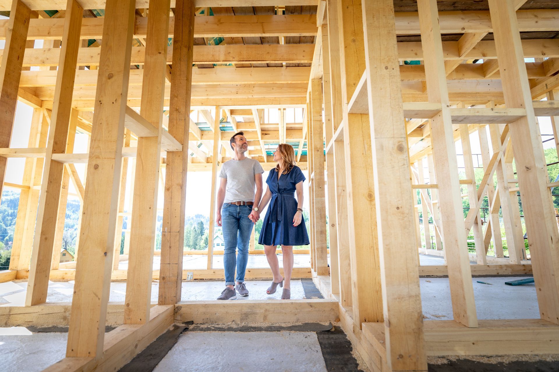 A man and a woman are holding hands in a wooden house under construction.