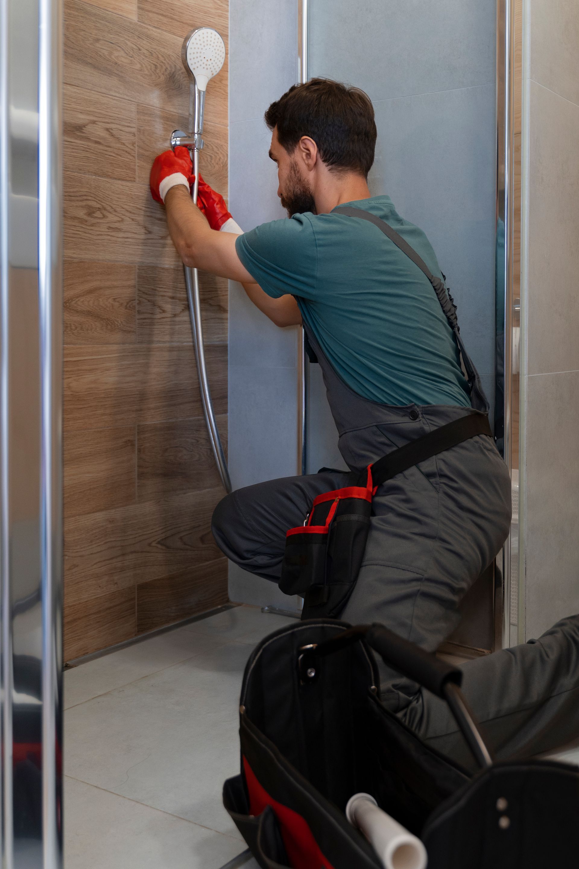 A man is fixing a shower head in a bathroom.