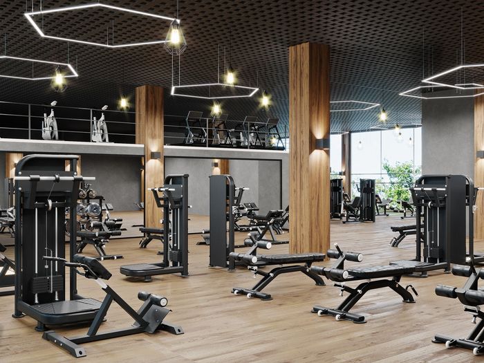 Gym interior with exercise machines, wooden floors, and modern lighting.