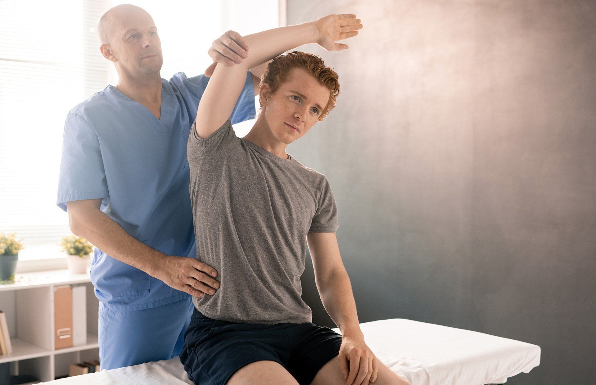 Man receiving shoulder mobility assessment from medical professional.
