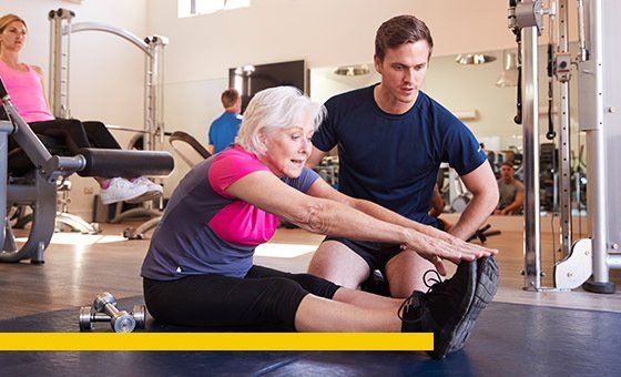 Woman stretching with trainer in gym.