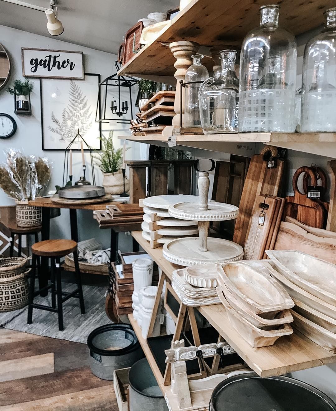 Shop interior with wooden shelves displaying home decor items and glass bottles.