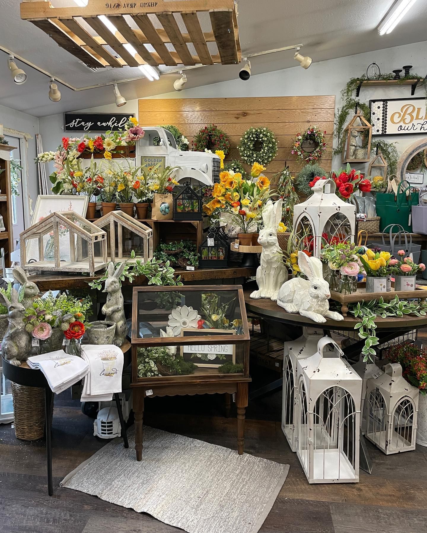 Flower shop display with floral arrangements, rabbits, lanterns, and wooden shelves.