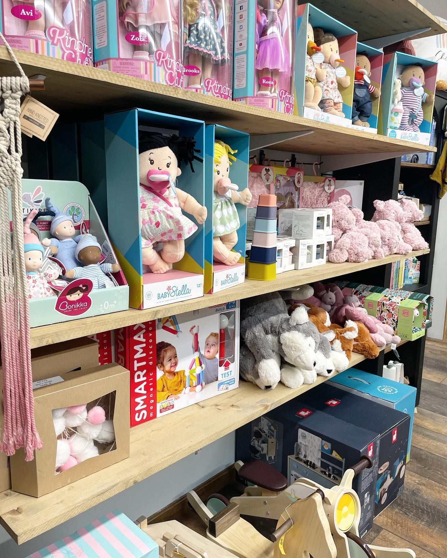 Shelves stocked with dolls, stuffed animals, and toy boxes in a store.