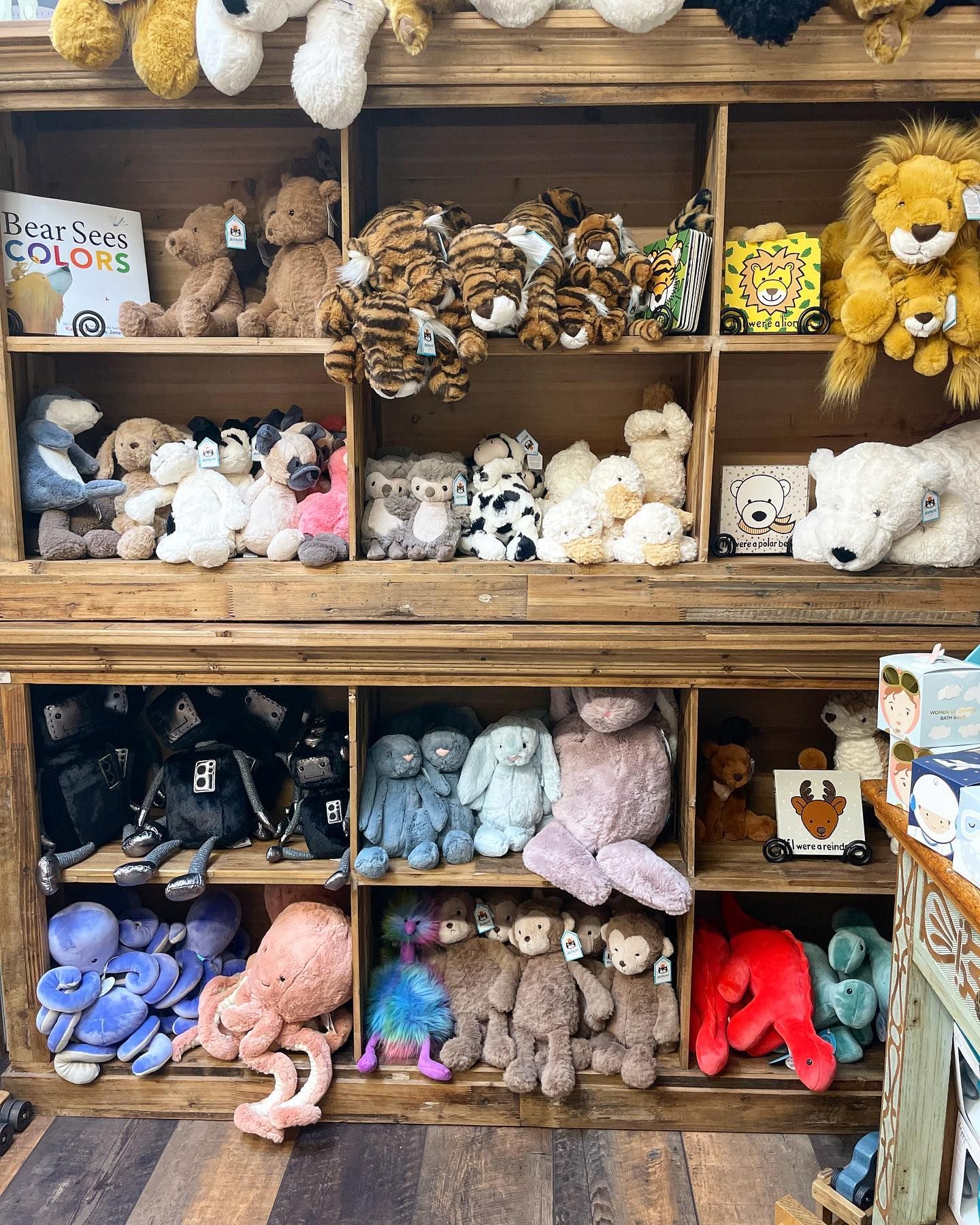 A wooden display cabinet filled with various plush animal toys of different colors and sizes.