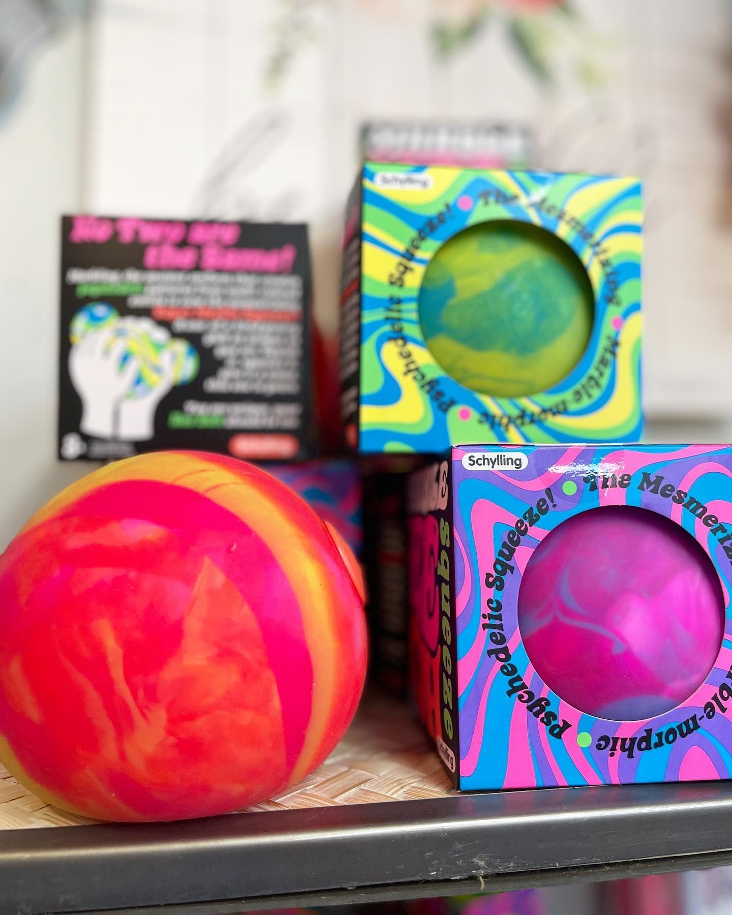 Marble-like stress balls in neon colors, with boxes, displayed on a shelf.